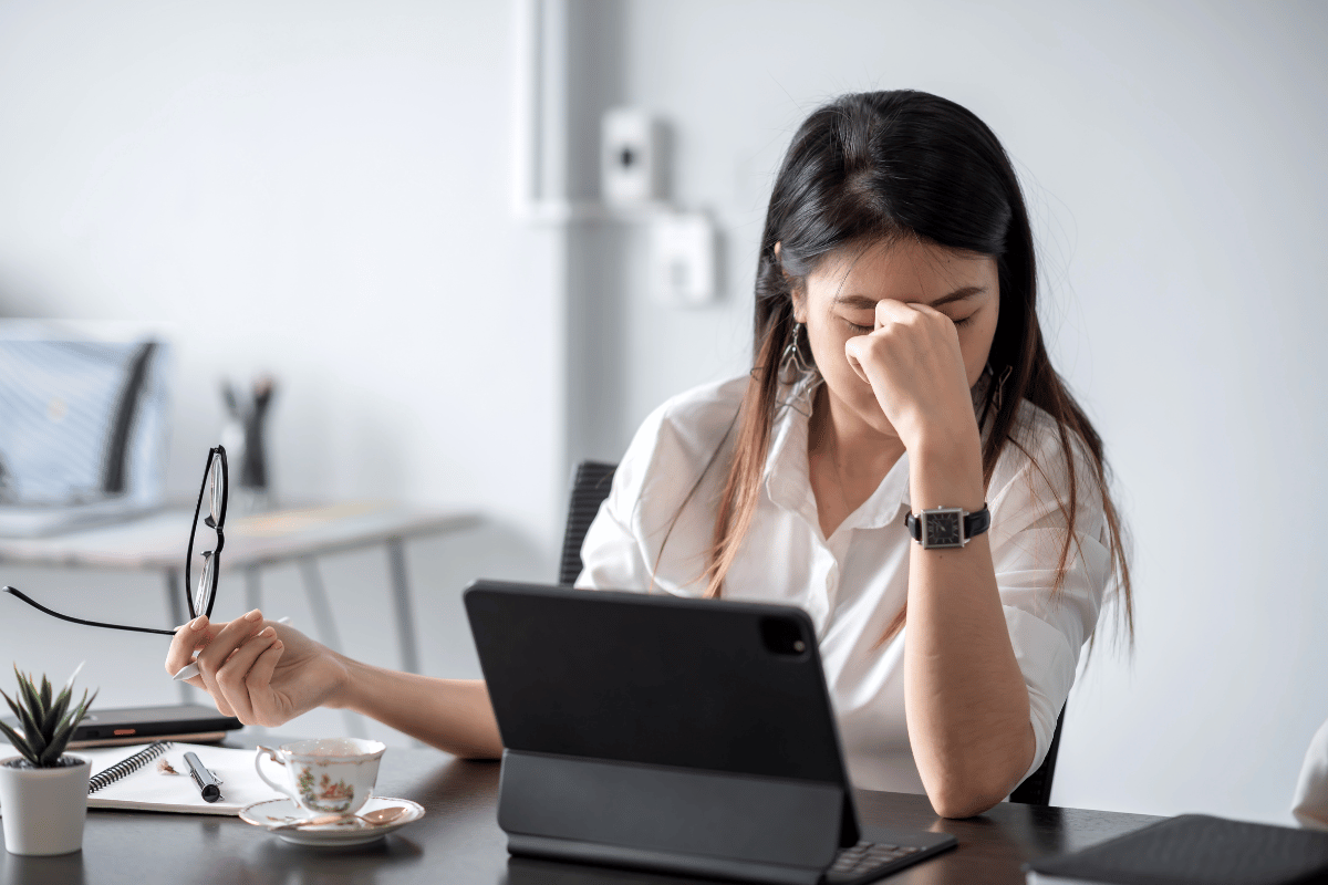 Woman taking off her glasses and holding hand to face due to eye strain