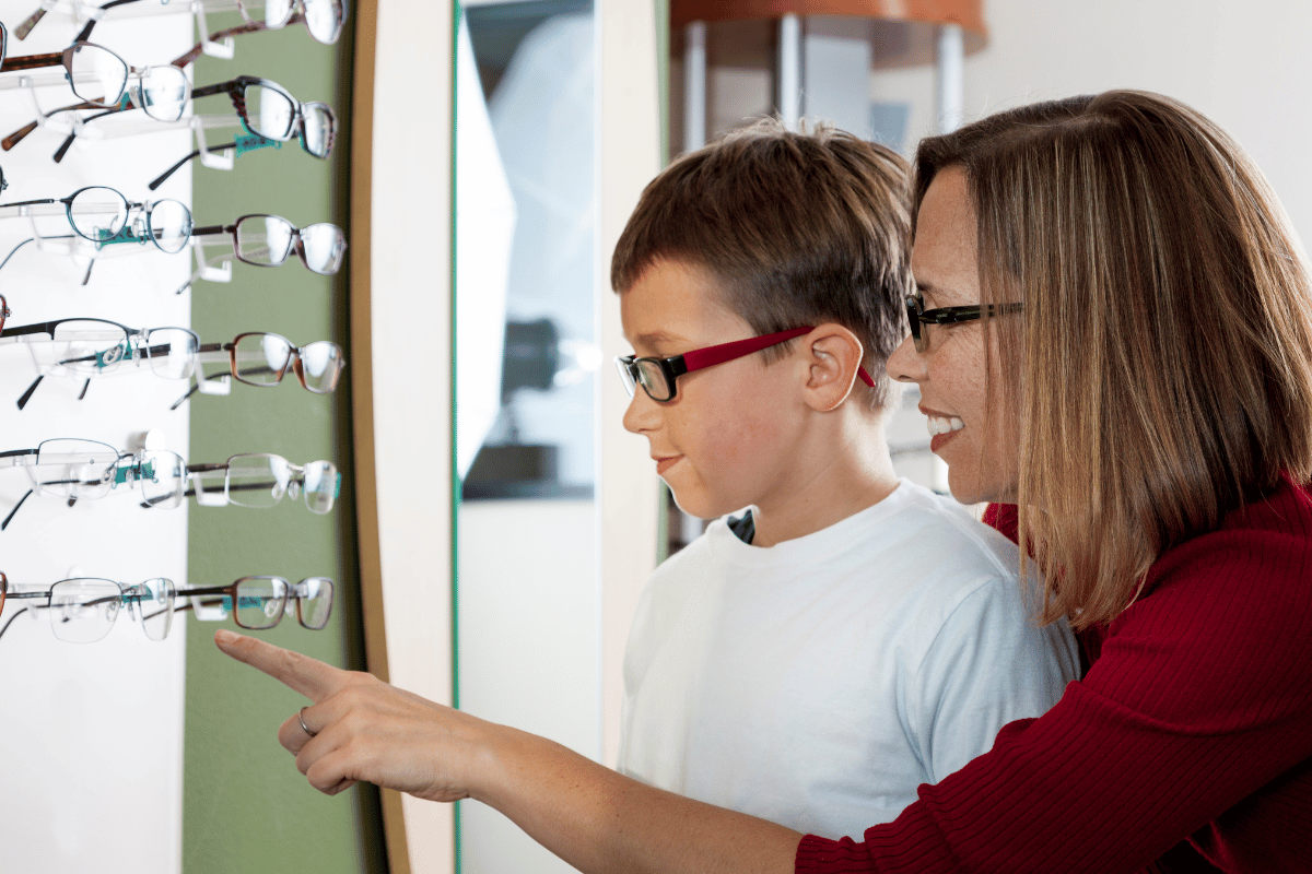 A young boy and his mom look at eyeglasses in an optical