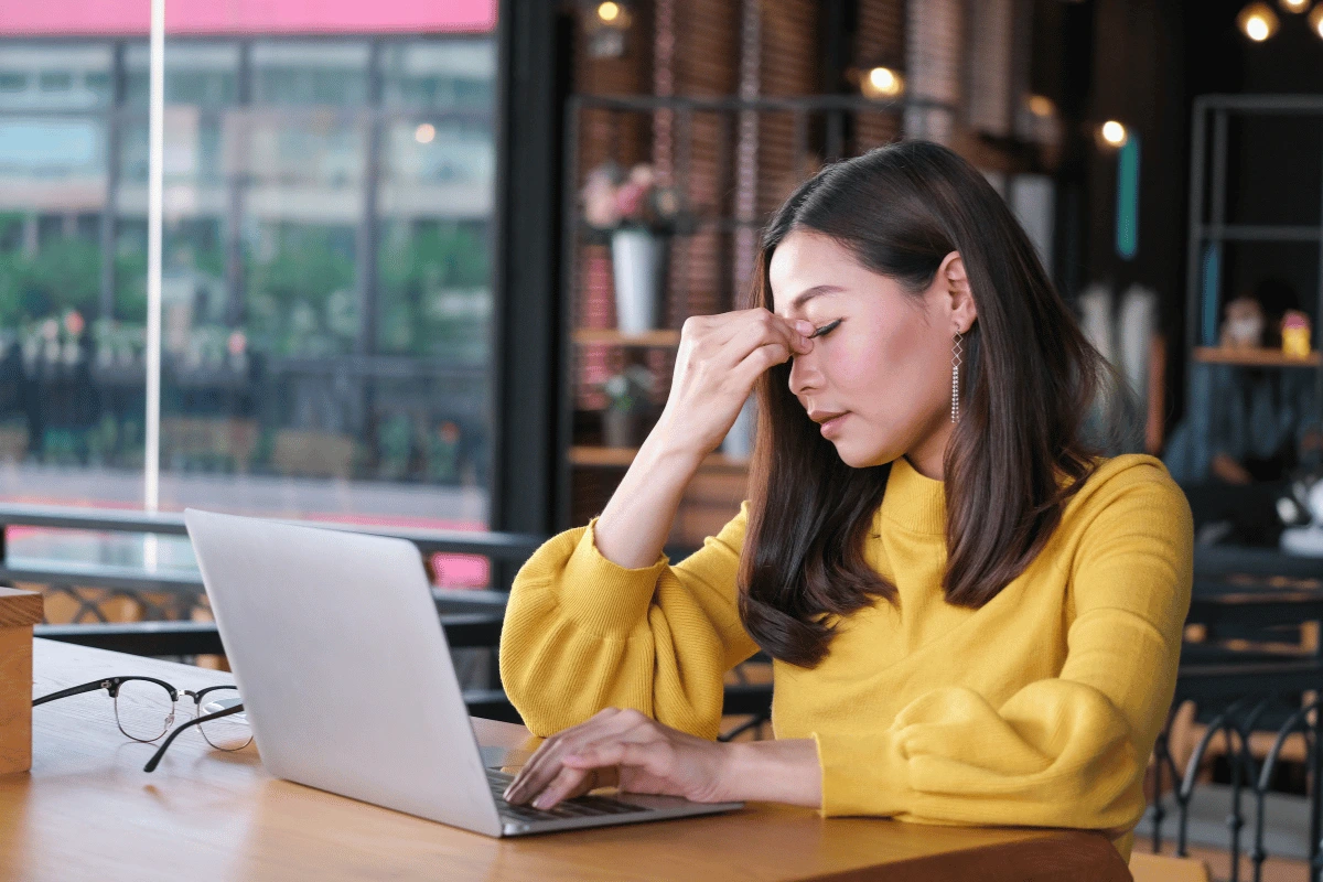 a woman in a cafe experiencing eye pain after computer use