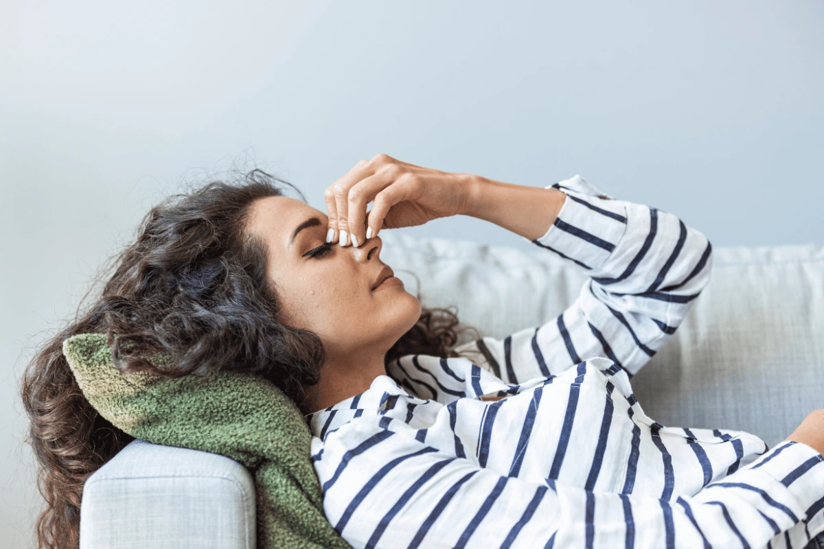 a woman lying on her couch with a severe headache
