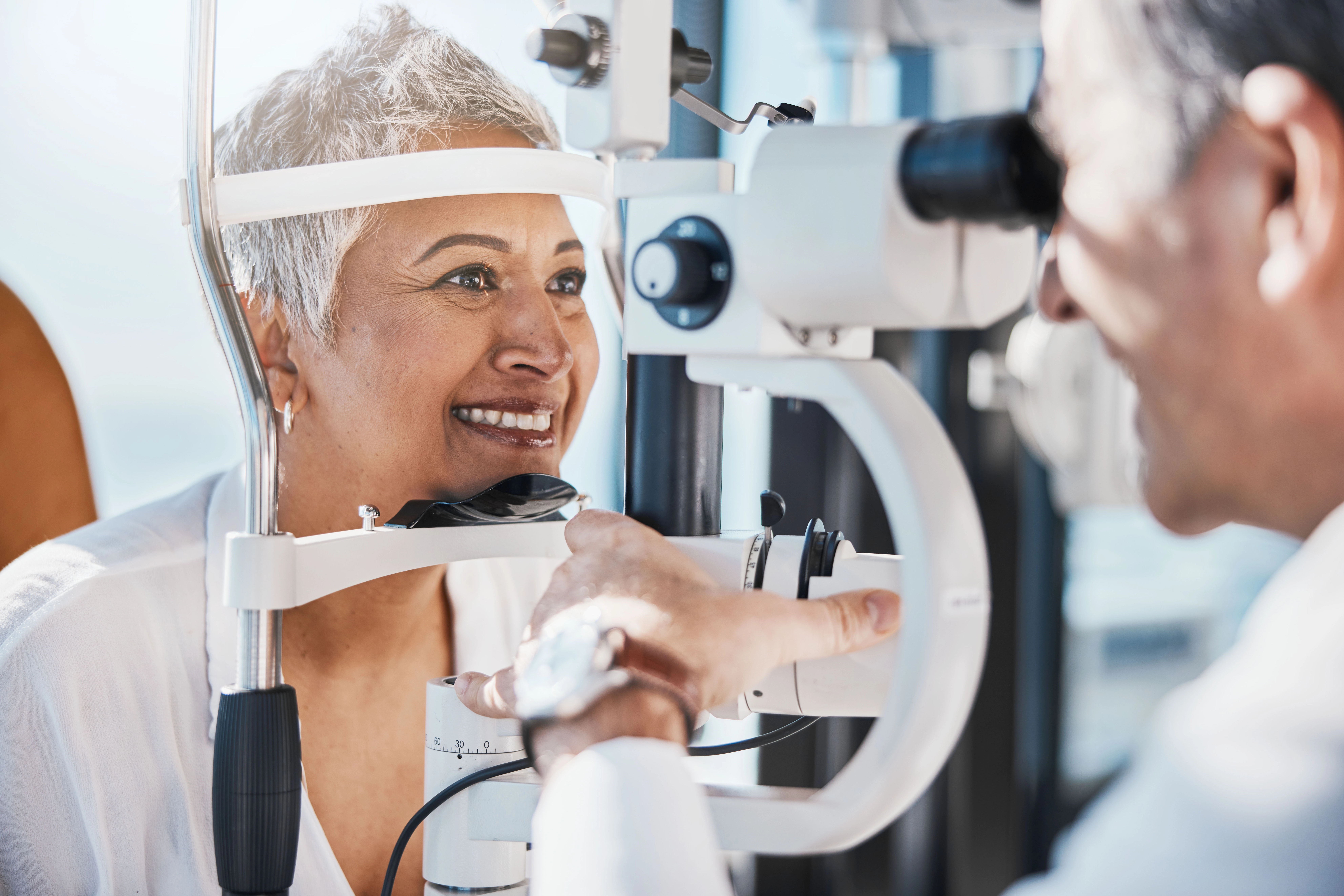 AdobeStock_574547561 A smiling older woman gets her eyes checked by her doctor.